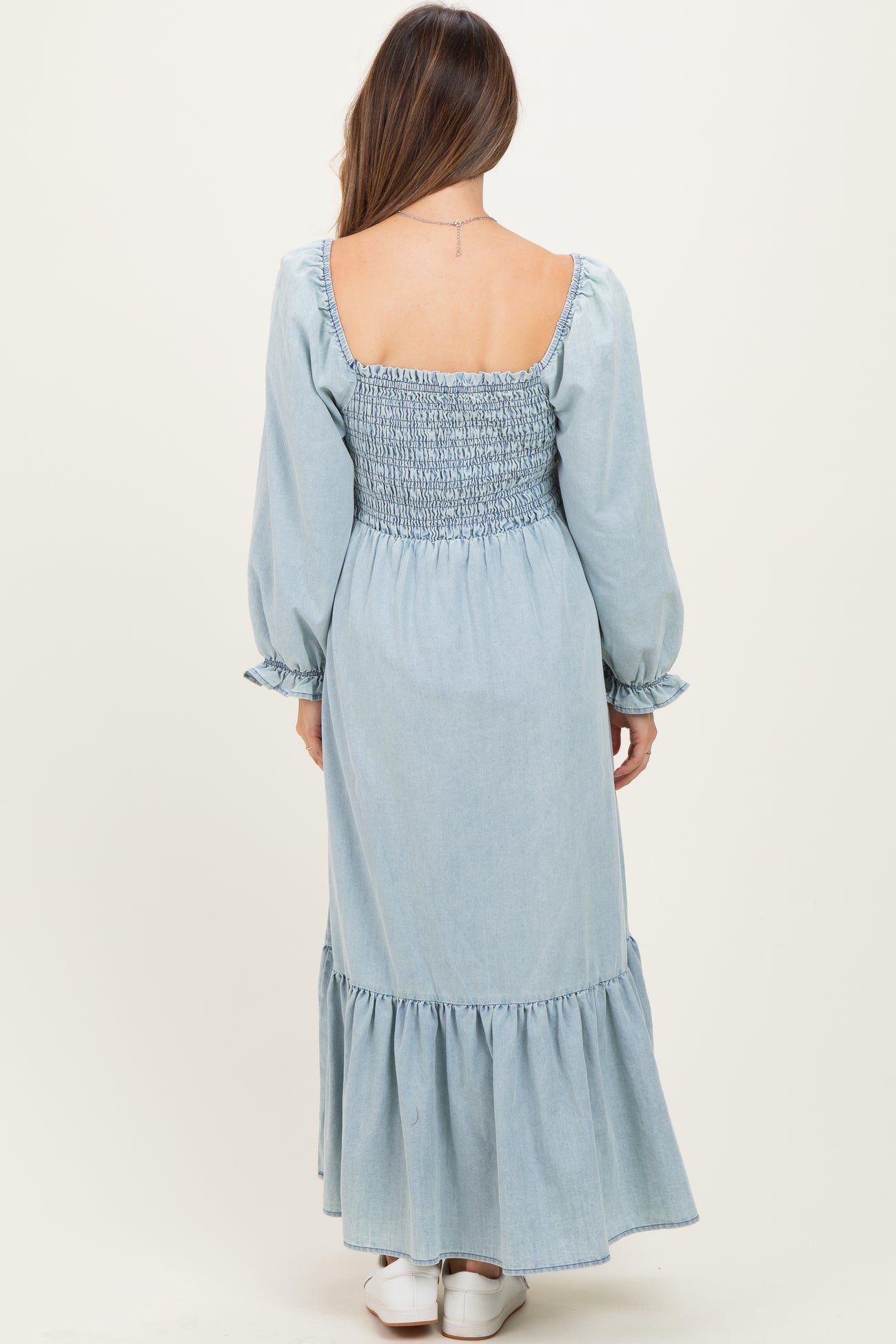 woman wearing a light blue maternity maxi dress with a smocked bodice and long sleeves, back view