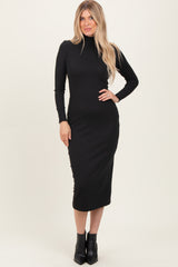 woman wearing a black long sleeve ribbed midi dress and black heeled ankle boots