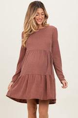 woman wearing a rust ribbed maternity dress with long sleeves and a tiered skirt, highlighting her baby bump