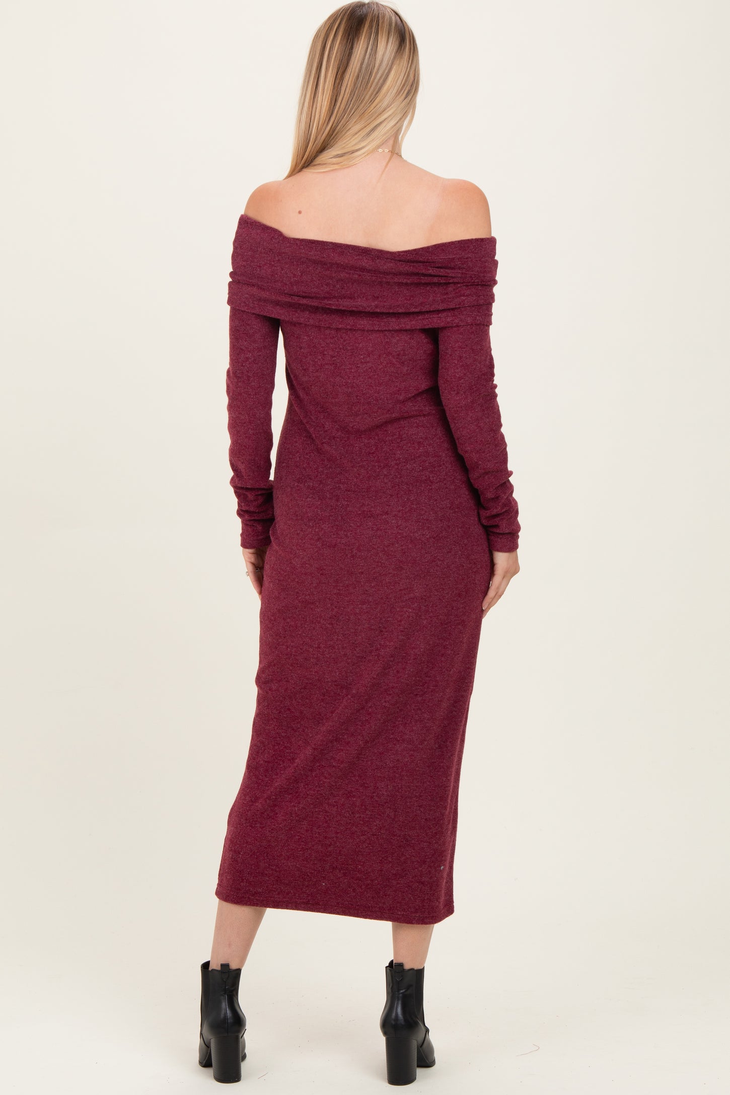 woman wearing a burgundy off-the-shoulder long sleeve midi dress with a fitted silhouette and ribbed detailing
