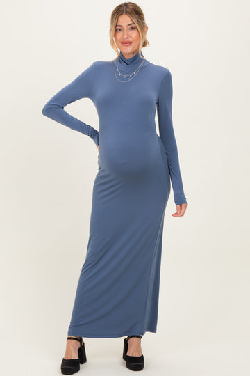 woman wearing a slate blue long sleeve maternity maxi dress with a turtleneck and a visible baby bump
