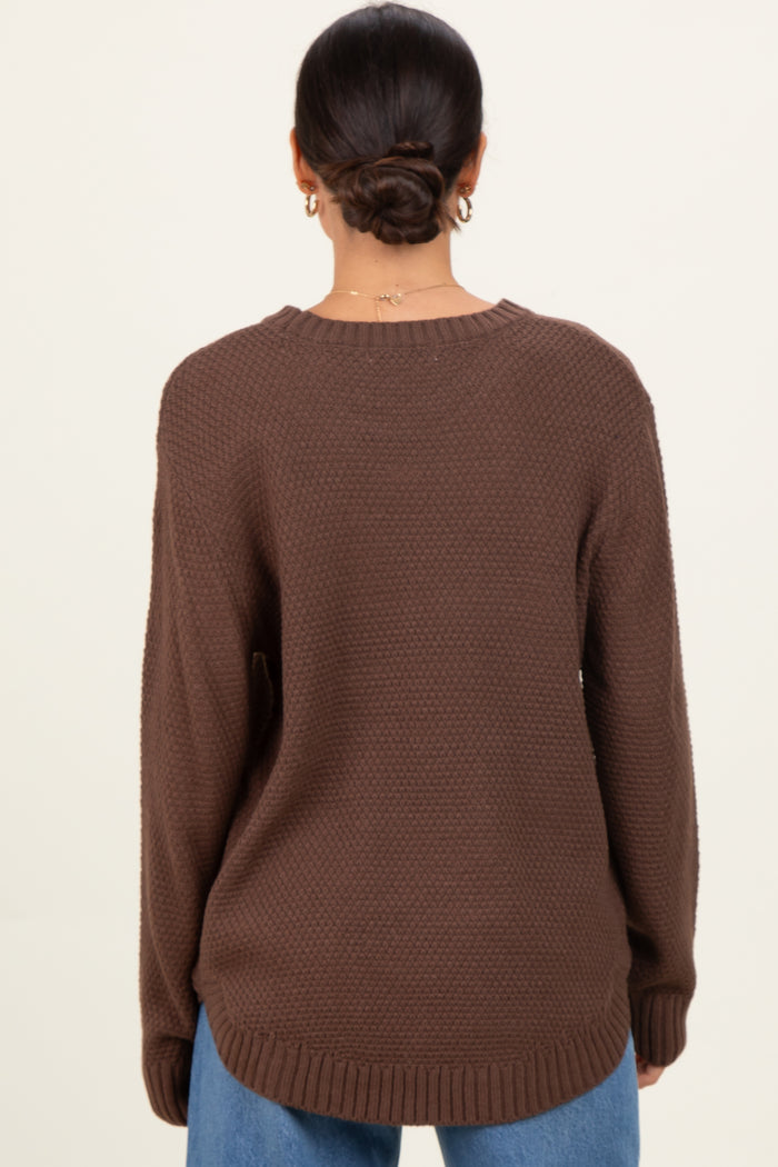 woman wearing a oversized brown knit sweater with a relaxed fit and long sleeves, viewed from the back