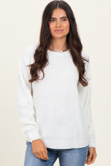 woman wearing a white knitted sweater with long sleeves and a round neckline paired with light blue jeans