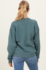 woman wearing a green maternity sweatshirt with a relaxed fit, shown from the back, paired with blue jeans