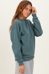 woman wearing a teal oversized sweatshirt with a crew neckline and relaxed fit, styled with gray bottoms
