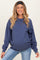 woman wearing a navy blue oversized maternity sweatshirt and showing her baby bump while smiling