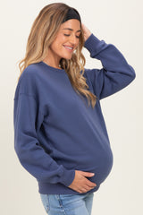 woman wearing a dark blue maternity sweatshirt and holding her baby bump