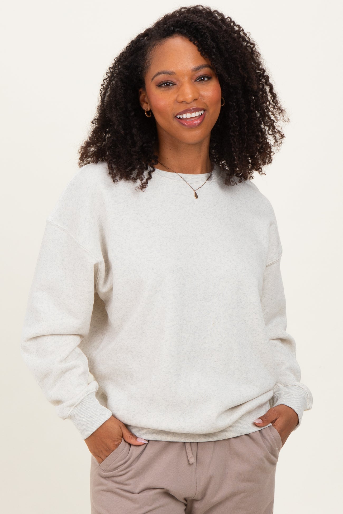 woman wearing a light gray oversized sweatshirt with cuffed sleeves and a round neckline