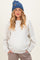 woman wearing a light gray maternity sweatshirt with a relaxed fit and holding her baby bump, paired with a blue knit beanie