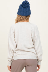 woman wearing a light gray maternity sweatshirt with a relaxed fit and back view, paired with a blue knitted beanie