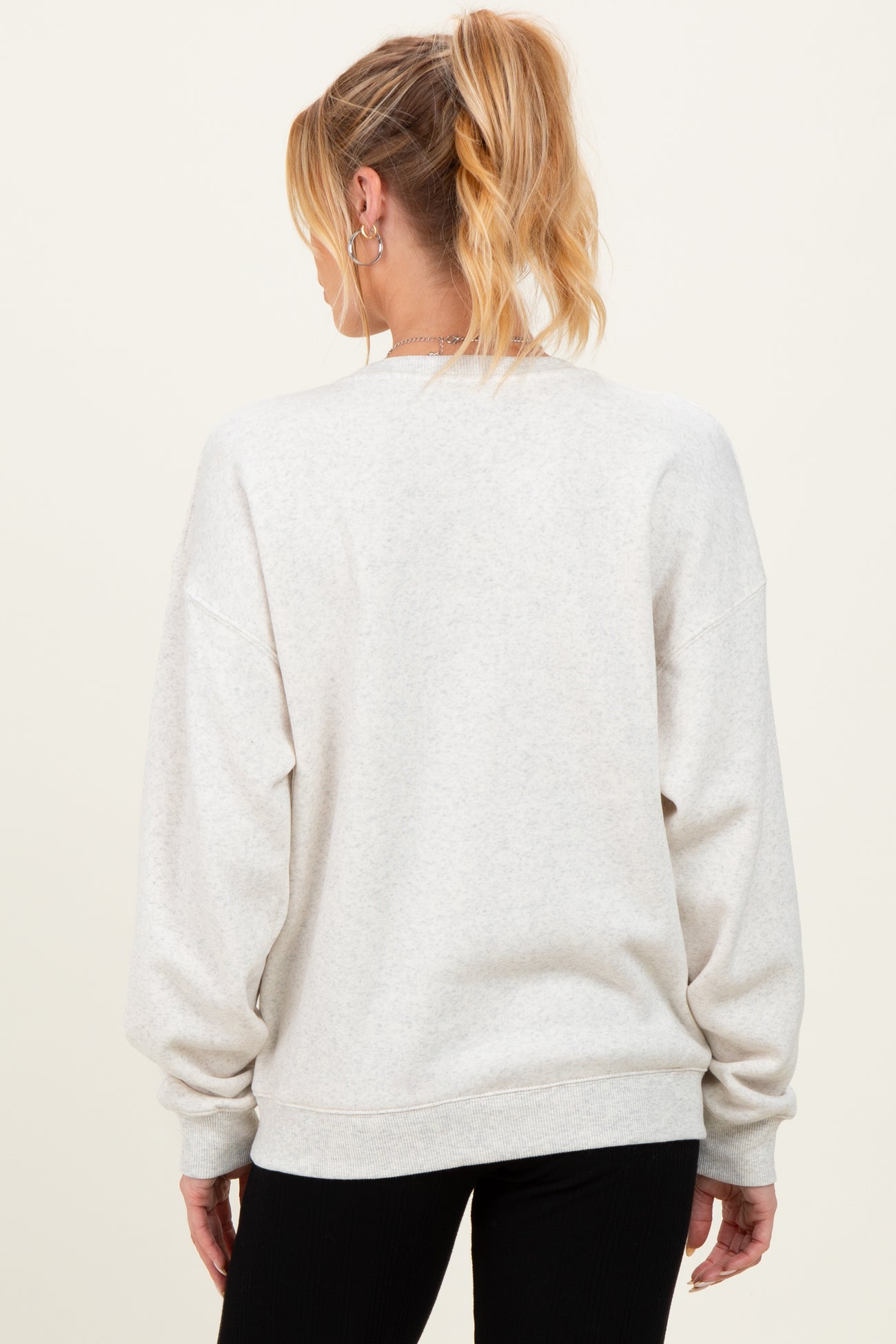 woman wearing a light gray oversized maternity sweatshirt, shown from the back, with loose sleeves and a relaxed fit