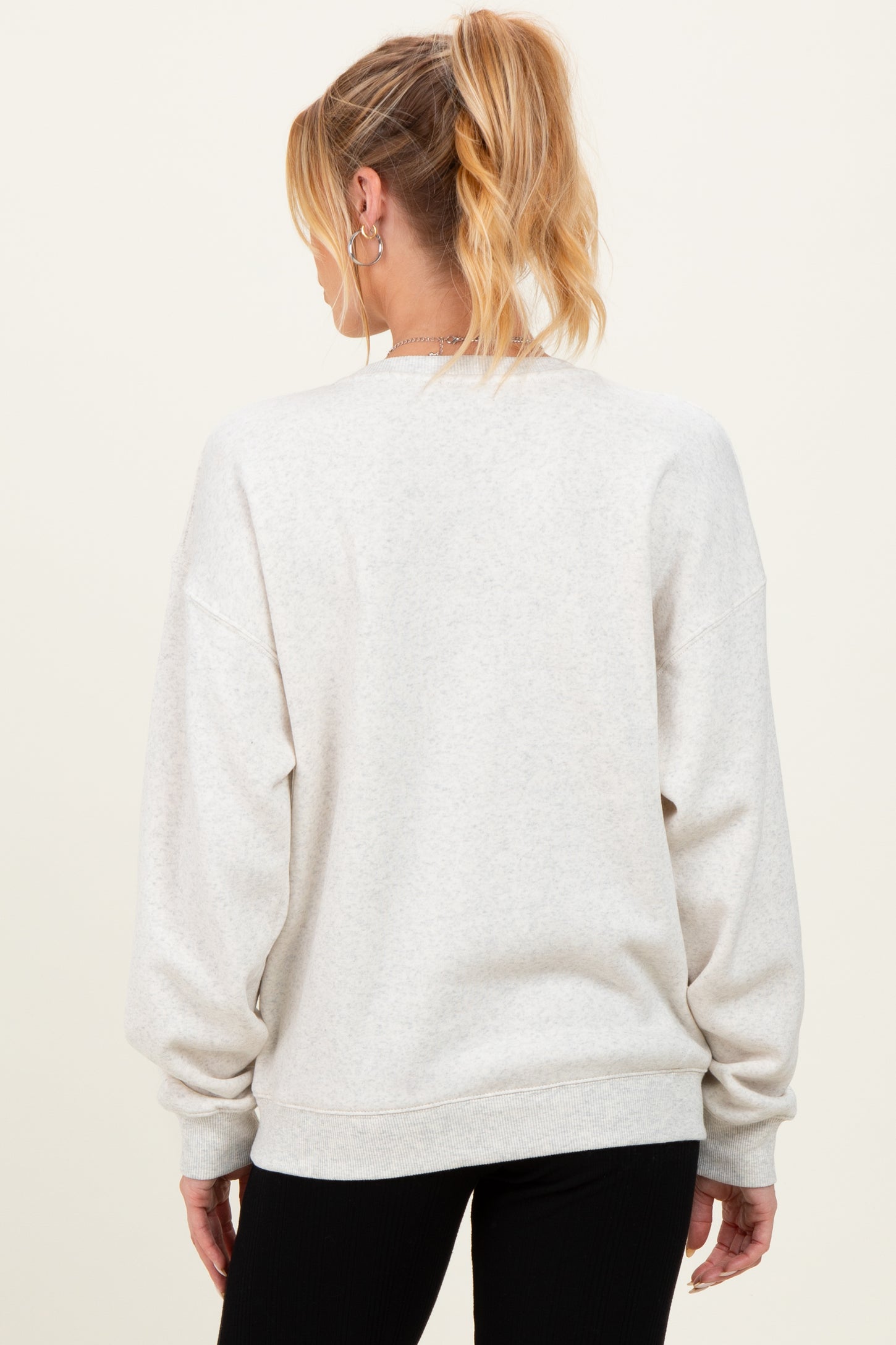 woman wearing a light gray oversized maternity sweatshirt, shown from the back, with loose sleeves and a relaxed fit