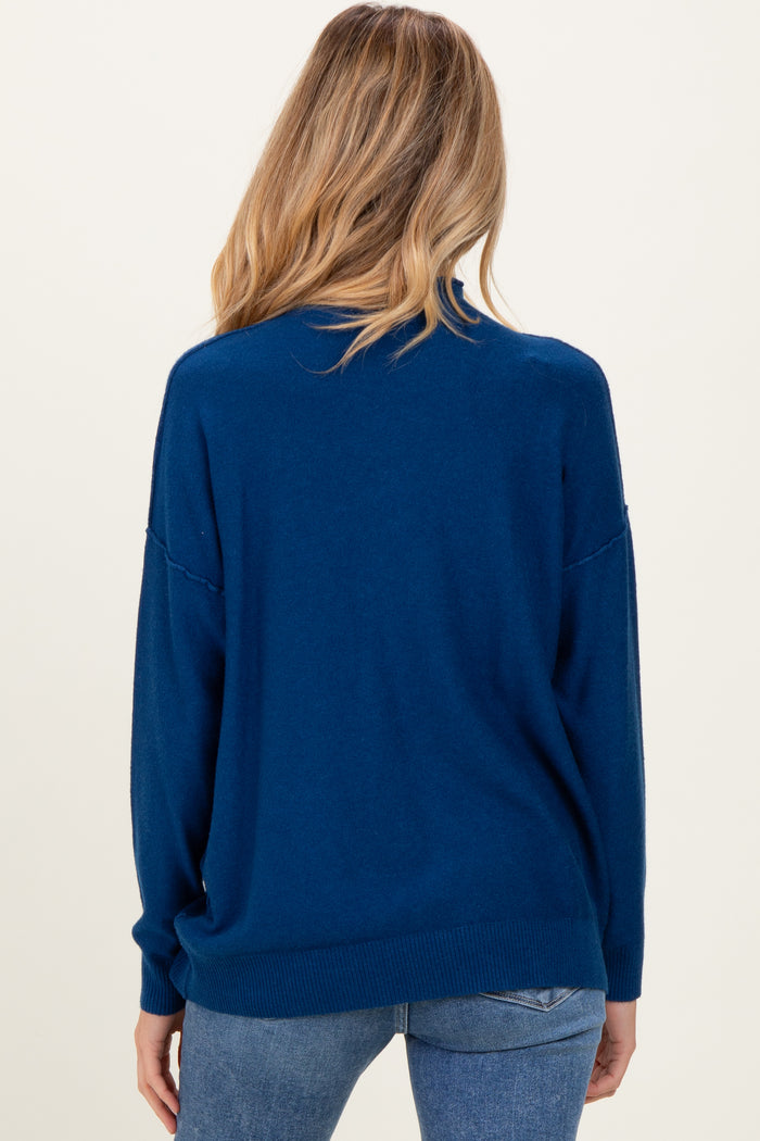 woman wearing a dark blue oversized maternity sweater, viewed from the back