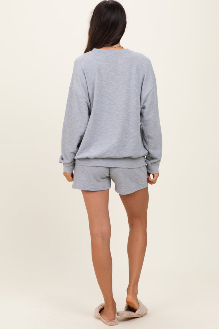 woman wearing a light grey oversized sweatshirt and matching shorts, viewed from the back