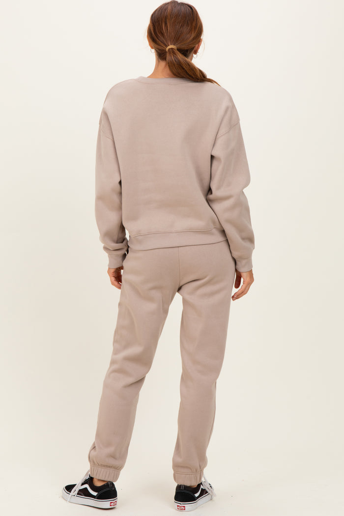 woman wearing a beige sweatshirt and matching sweatpants, seen from the back, casual loungewear style