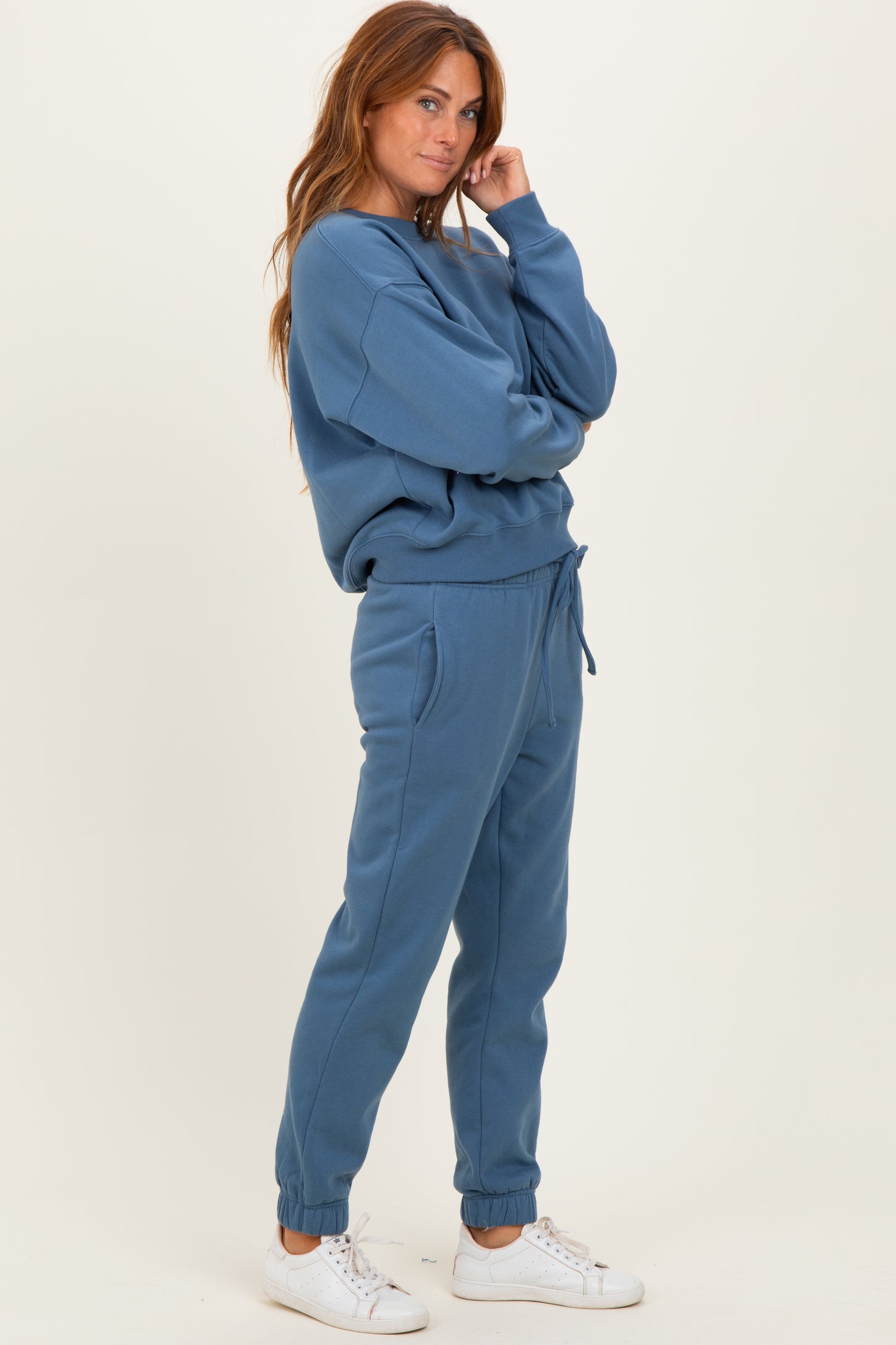 woman wearing a blue matching sweatshirt and jogger set with elastic cuffs and a drawstring waist