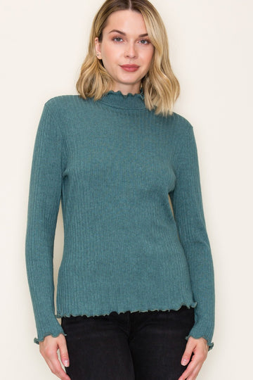 woman wearing a teal ribbed long sleeve mock neck top with scalloped edges and a slim fit