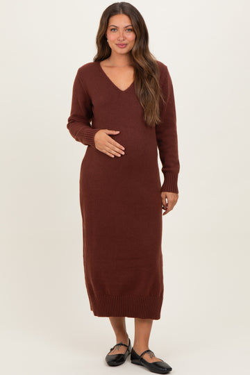 woman wearing a burgundy long sleeve maternity dress with a v-neck and holding her baby bump