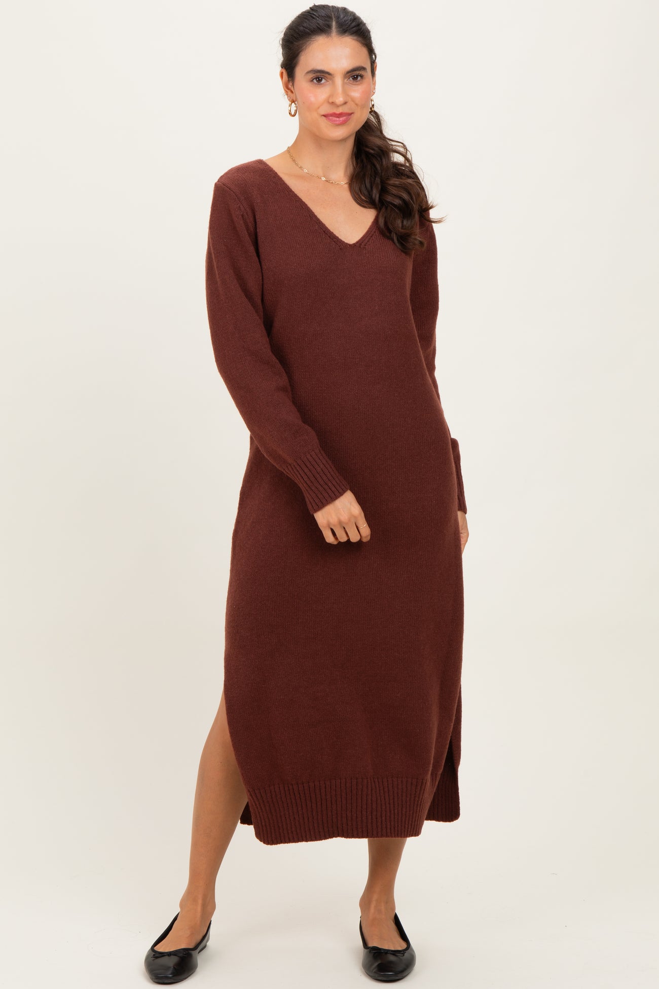 woman wearing a brown v-neck long sleeve sweater dress with side slits and a relaxed fit