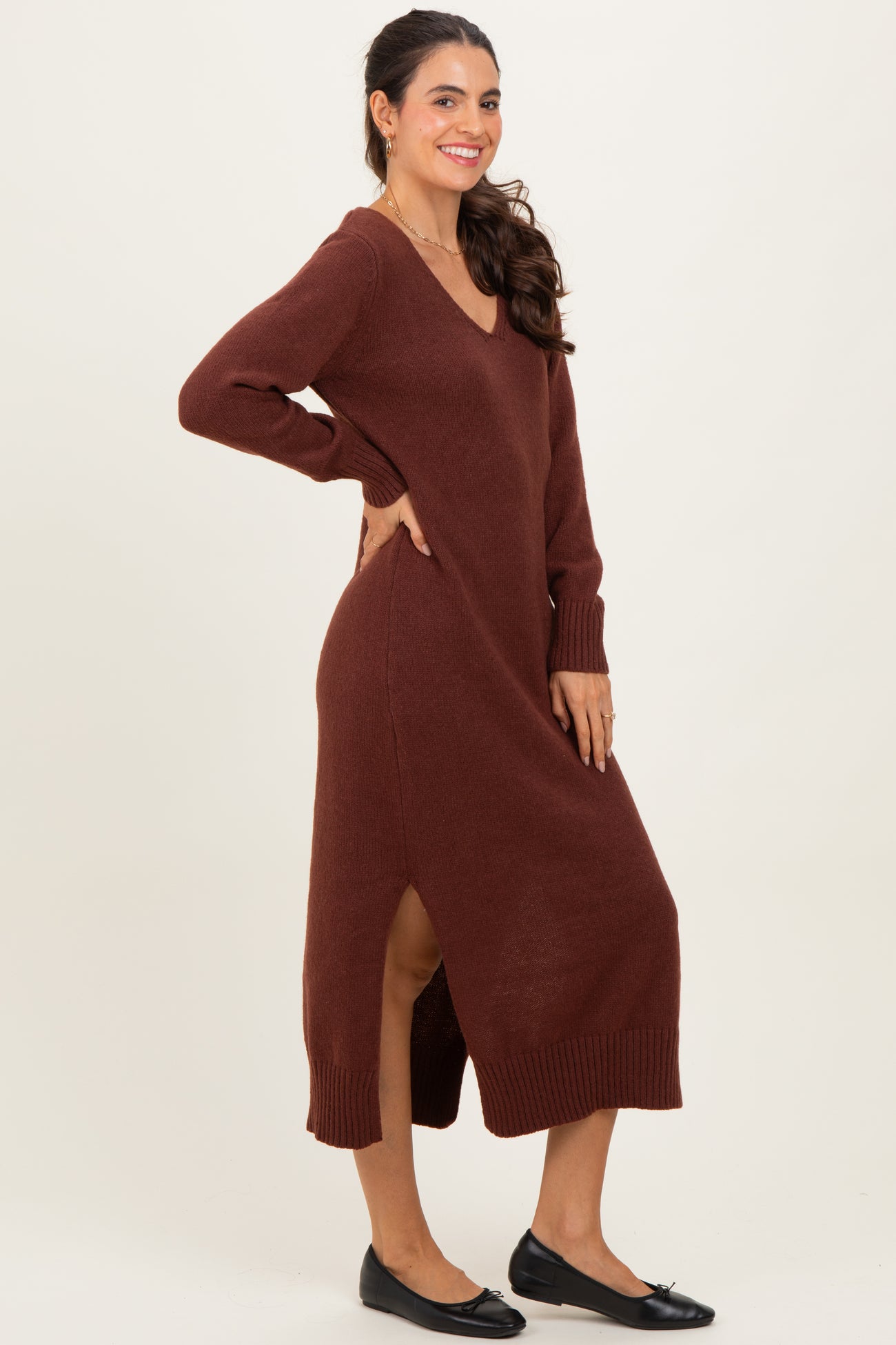 woman wearing a brown v-neck long sleeve maxi sweater dress with side slits and black flats