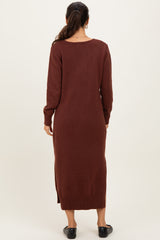 woman wearing a long brown sweater dress with long sleeves and side slits, viewed from the back
