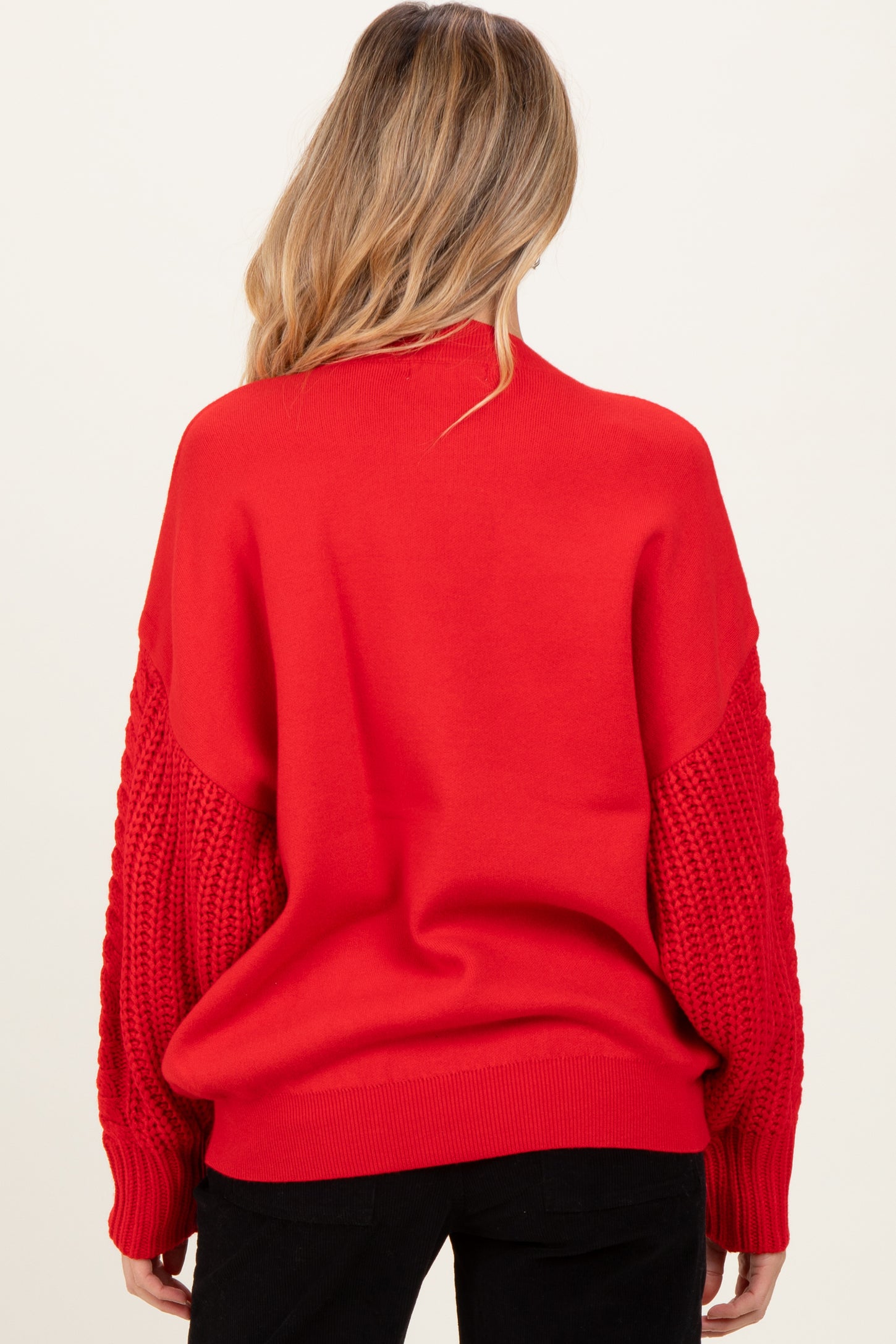woman wearing a red maternity sweater with textured knit sleeves, showing the back view