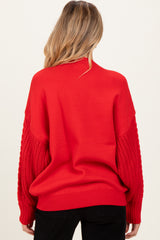 woman wearing a red maternity sweater with textured knit sleeves, showing the back view