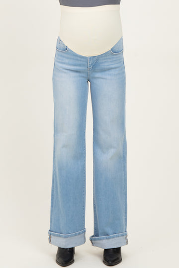 woman wearing light blue flared maternity jeans with a stretchy belly band, slightly rolled cuffs at the ankles