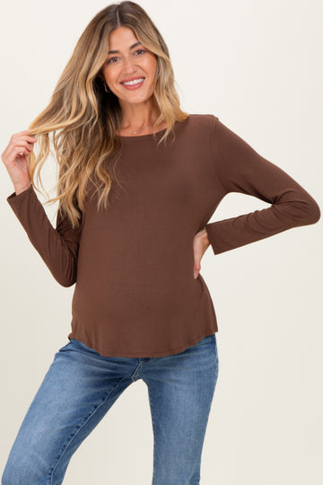 woman wearing a brown long sleeve maternity top and showing her baby bump with a smile