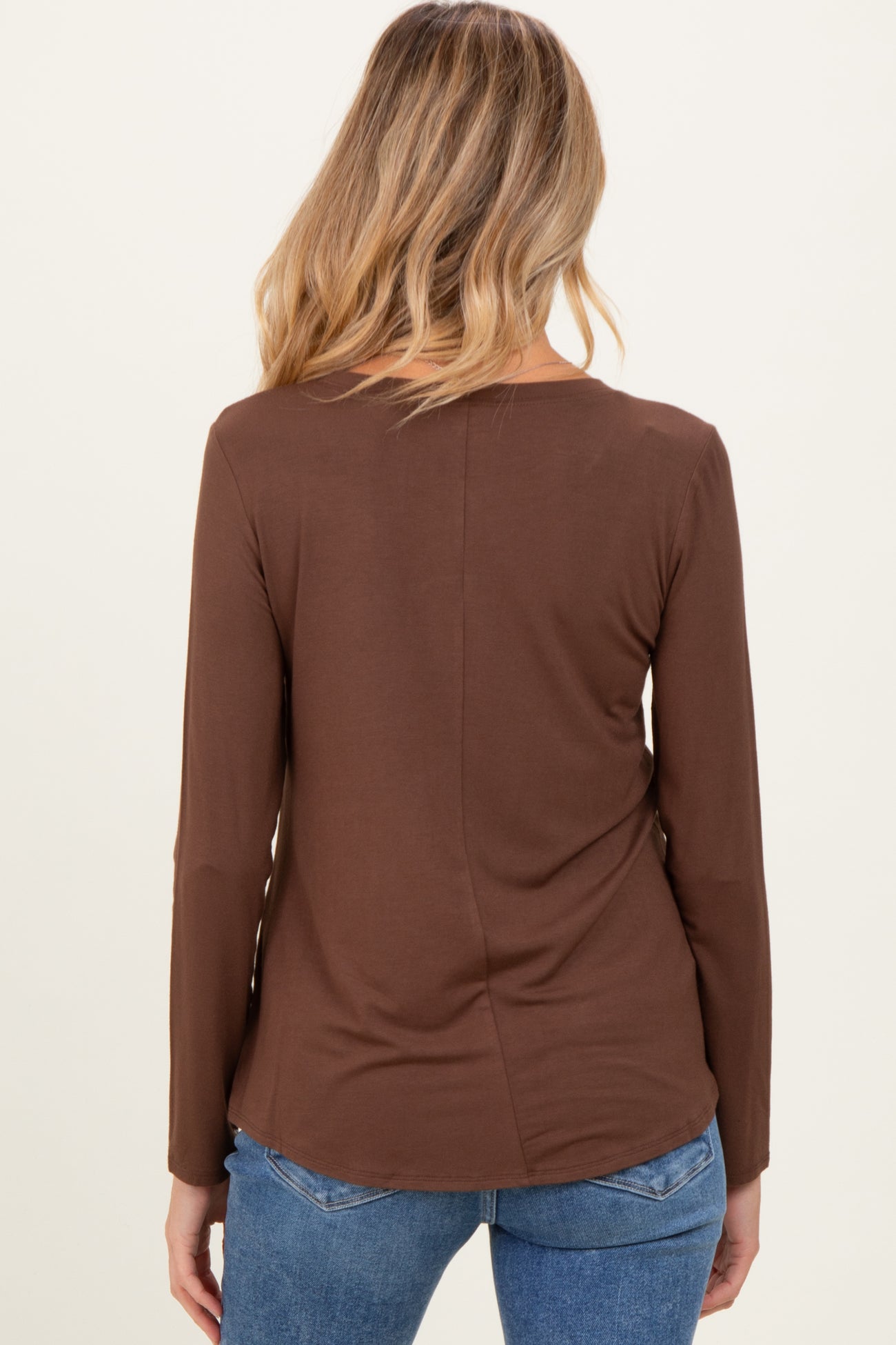 woman wearing a brown long sleeve maternity top, viewed from the back with a relaxed fit and rounded hemline