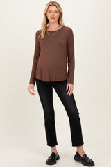woman wearing a brown long sleeve maternity top and black jeans, showing her baby bump