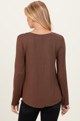 woman wearing a brown long sleeve maternity top, showing the back view with a curved hemline