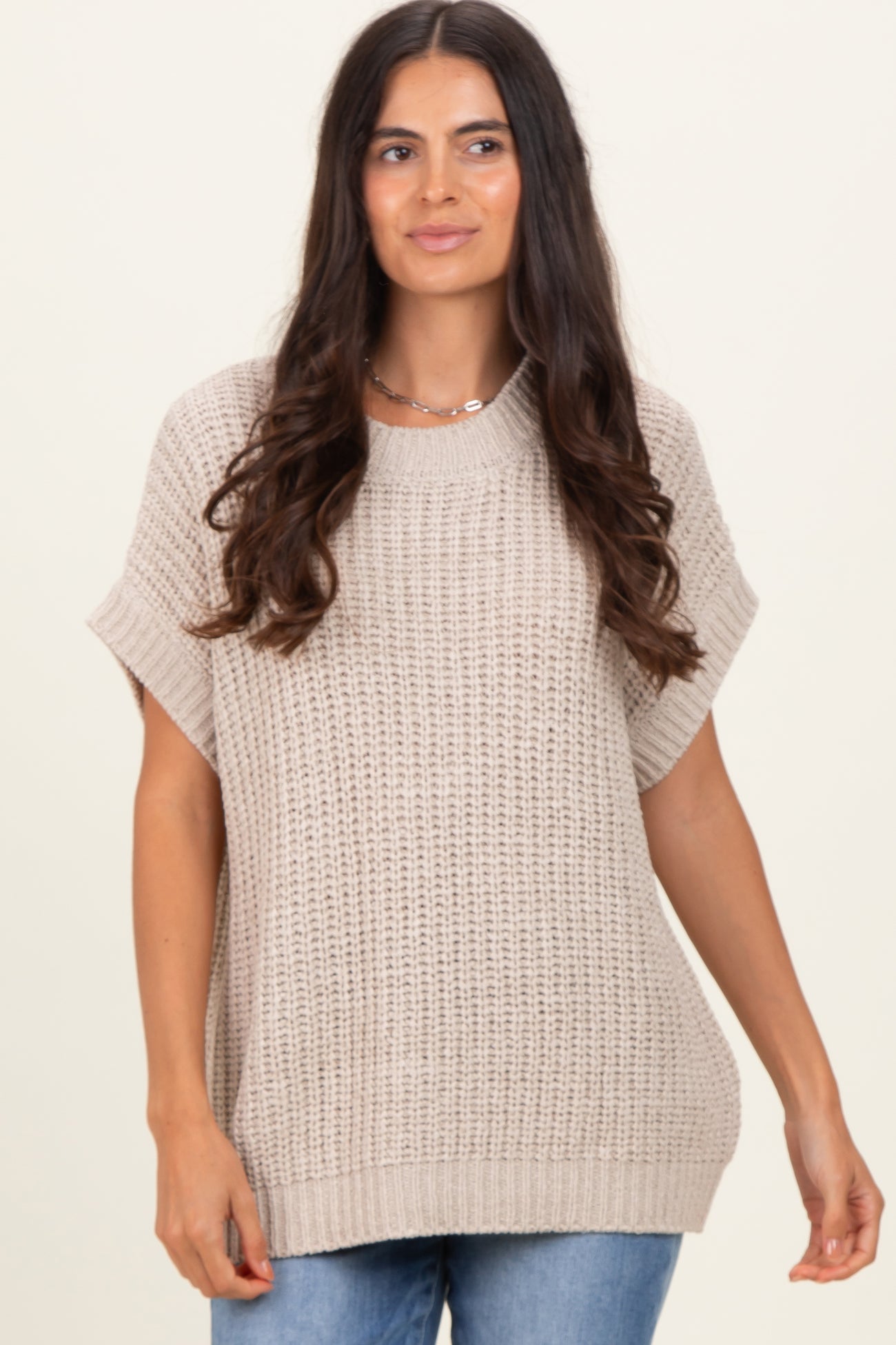 woman wearing a beige oversized knitted sweater with short sleeves and a relaxed fit