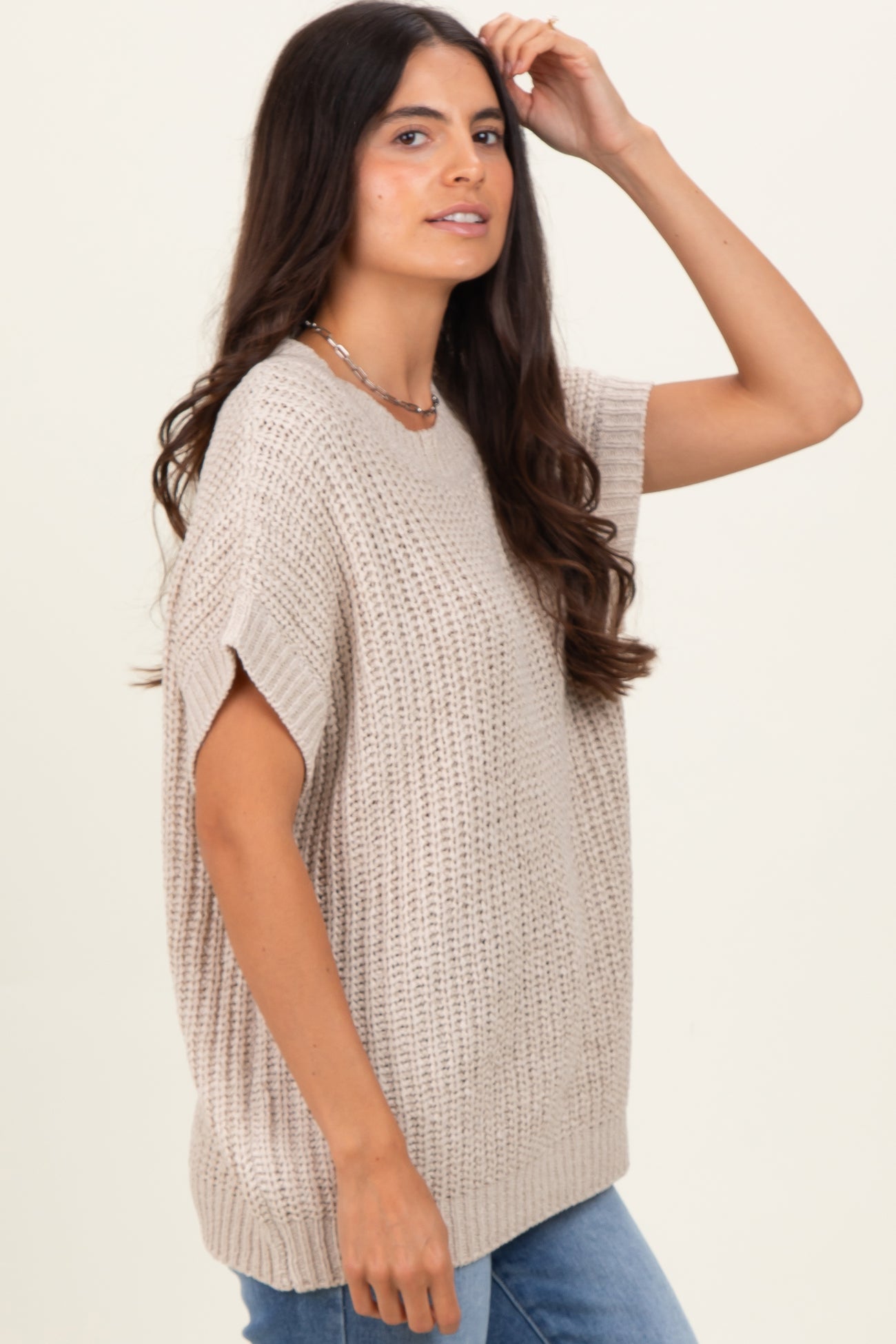 woman wearing a beige knitted oversized sweater with short sleeves and a relaxed fit