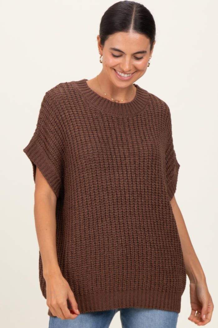 woman wearing a brown oversized knit sweater with short sleeves and a round neckline, paired with blue jeans