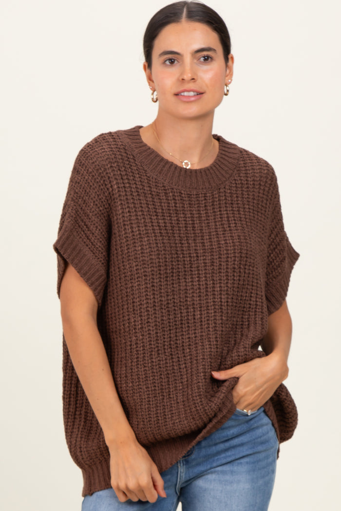 woman wearing a brown oversized knit sweater with short sleeves and a round neckline, paired with blue jeans