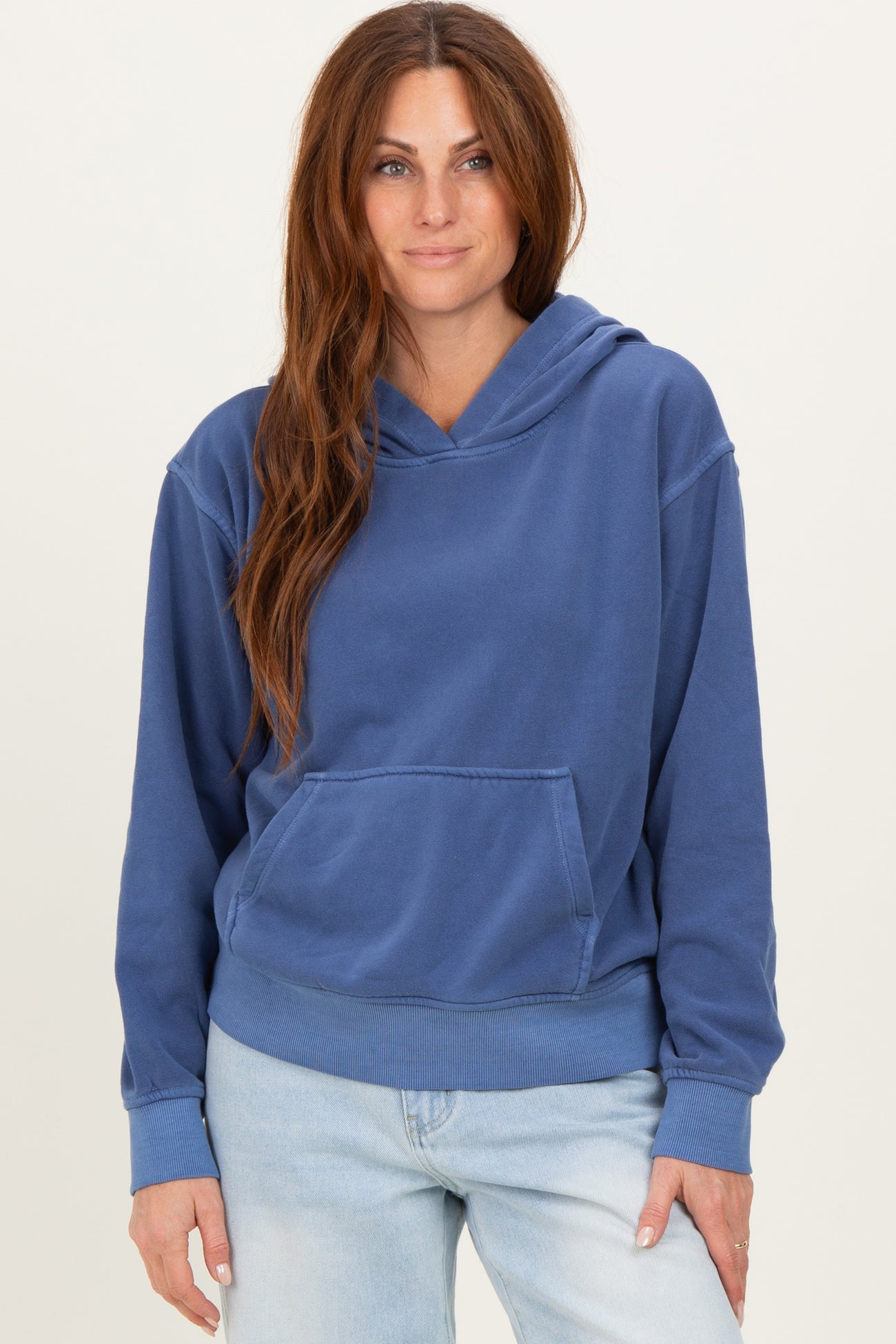 woman wearing a blue oversized hoodie with a front pocket and a relaxed fit, paired with light denim jeans