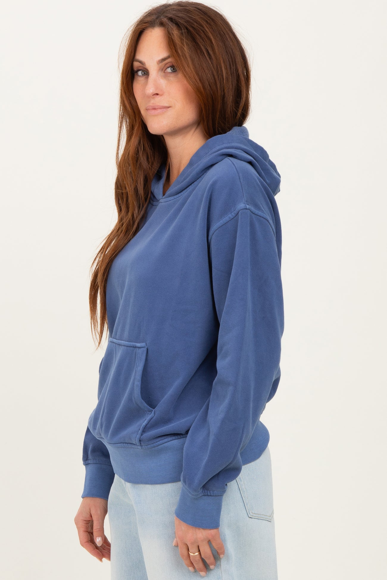 woman wearing a blue hooded sweatshirt with a front pocket and relaxed fit