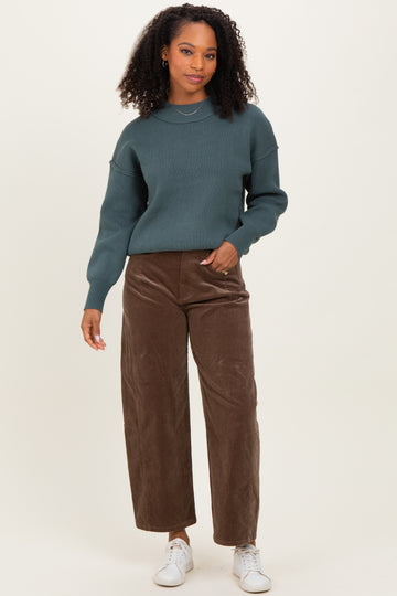 woman wearing a dark teal knitted sweater and brown wide-leg corduroy pants with white sneakers