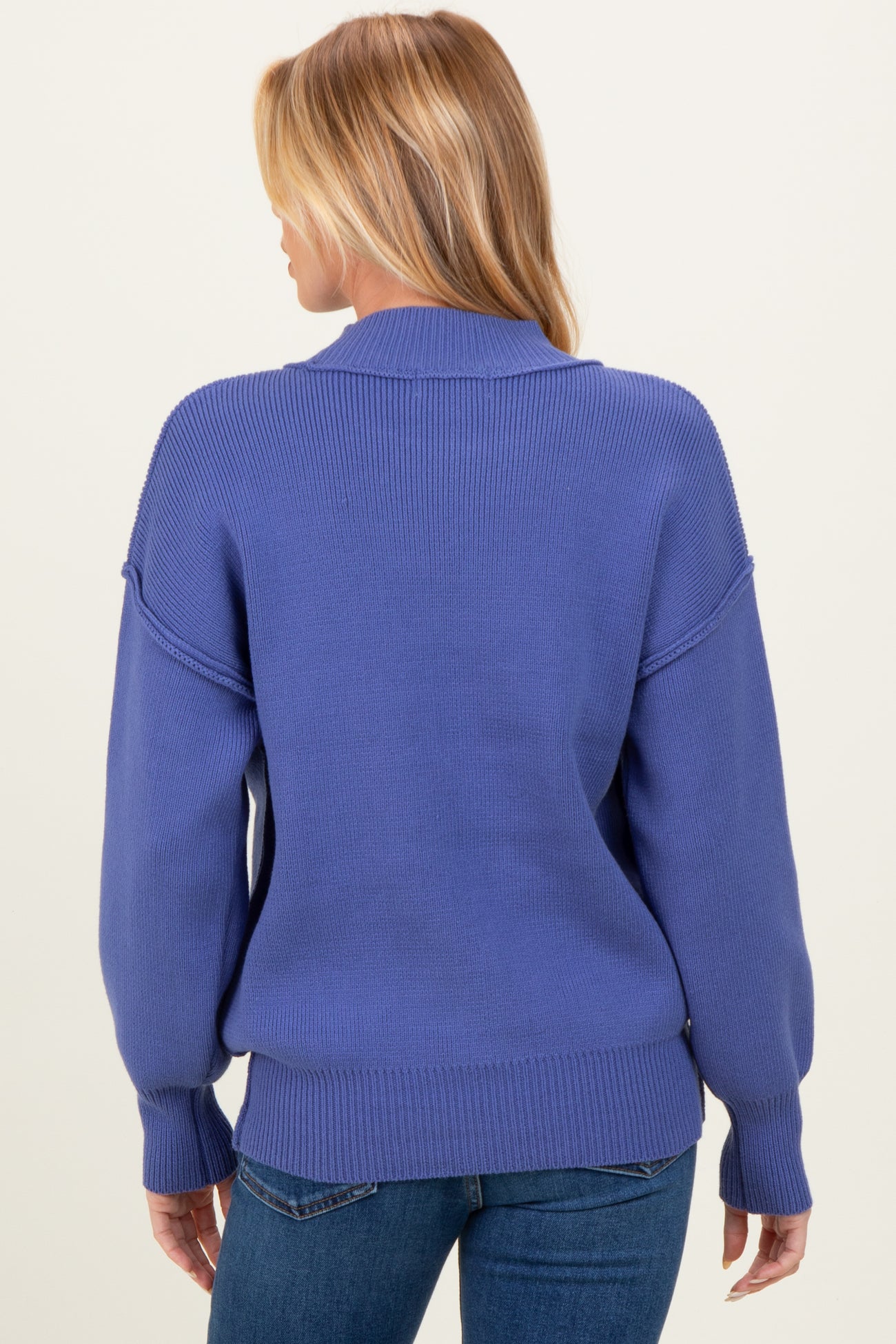 woman wearing a blue oversized maternity sweater with a relaxed fit and dropped shoulders, seen from the back