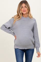 woman wearing a cozy light gray maternity sweater with a relaxed fit and visible baby bump