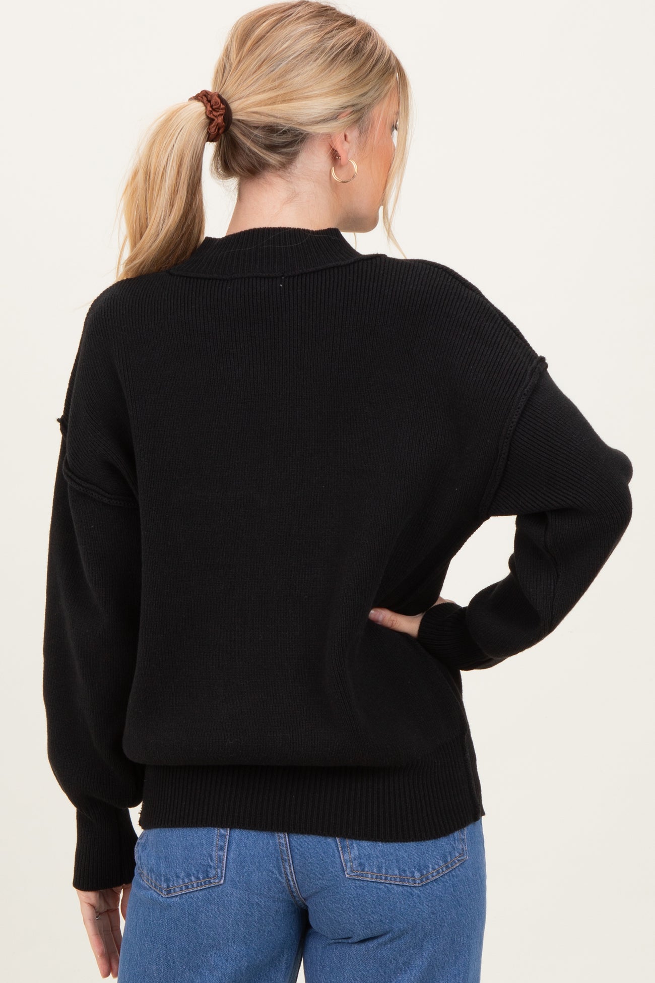 woman wearing a black oversized sweater, viewed from the back, with dropped shoulders and ribbed details