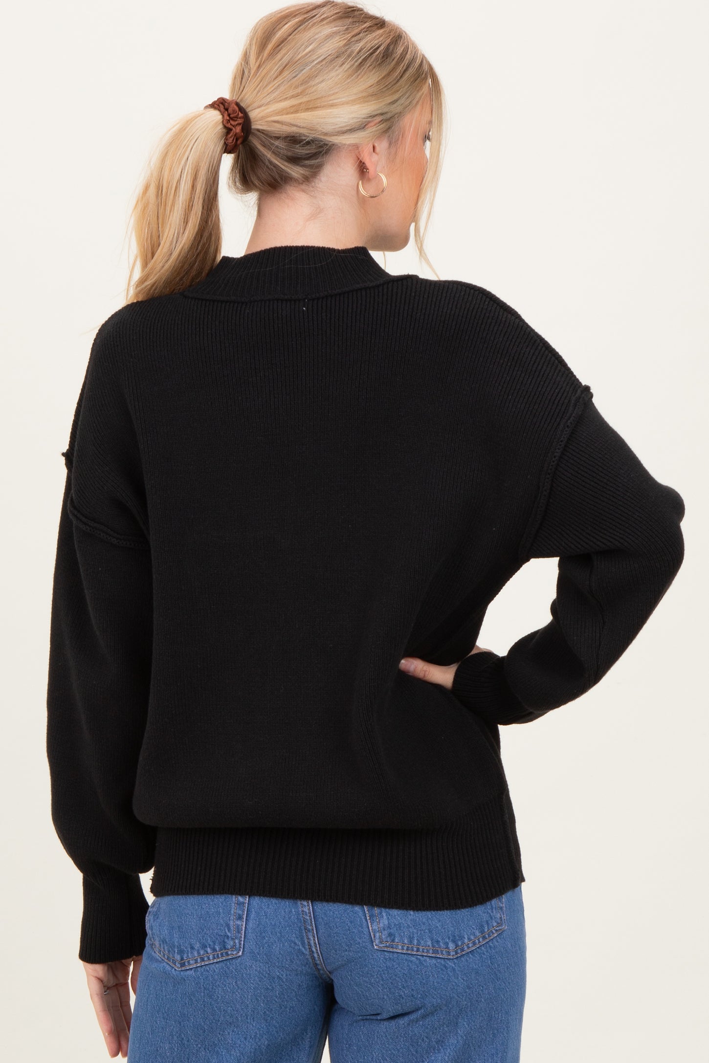 woman wearing a black oversized sweater, viewed from the back, with dropped shoulders and ribbed details