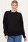 woman wearing a black oversized knit sweater with a mock neck and relaxed fit, paired with denim jeans