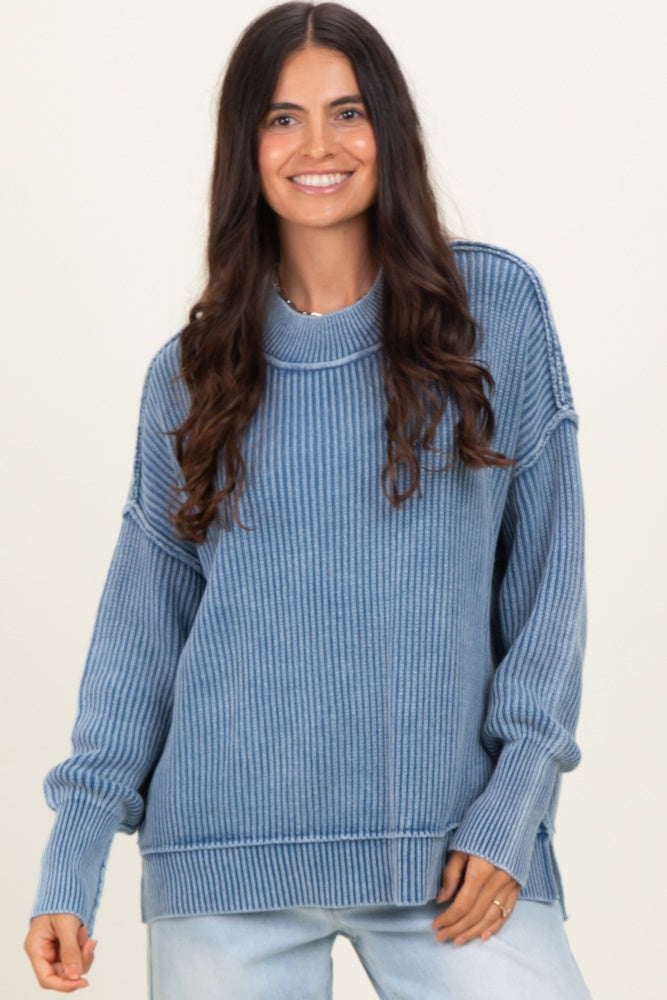 woman wearing a blue ribbed oversized sweater with a high neckline and side slits
