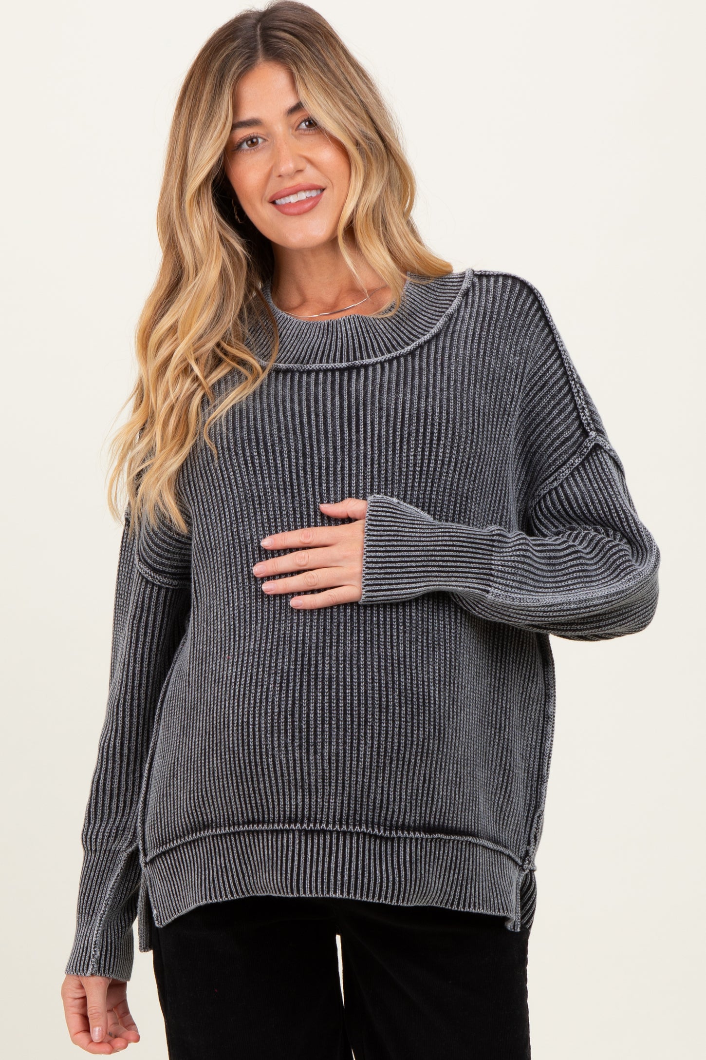 woman wearing a gray striped maternity sweater and holding her baby bump