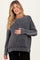 woman wearing a gray striped maternity sweater and holding her baby bump