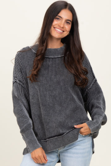 woman wearing a gray striped oversized sweater with a high neckline and dropped shoulders, smiling at the camera