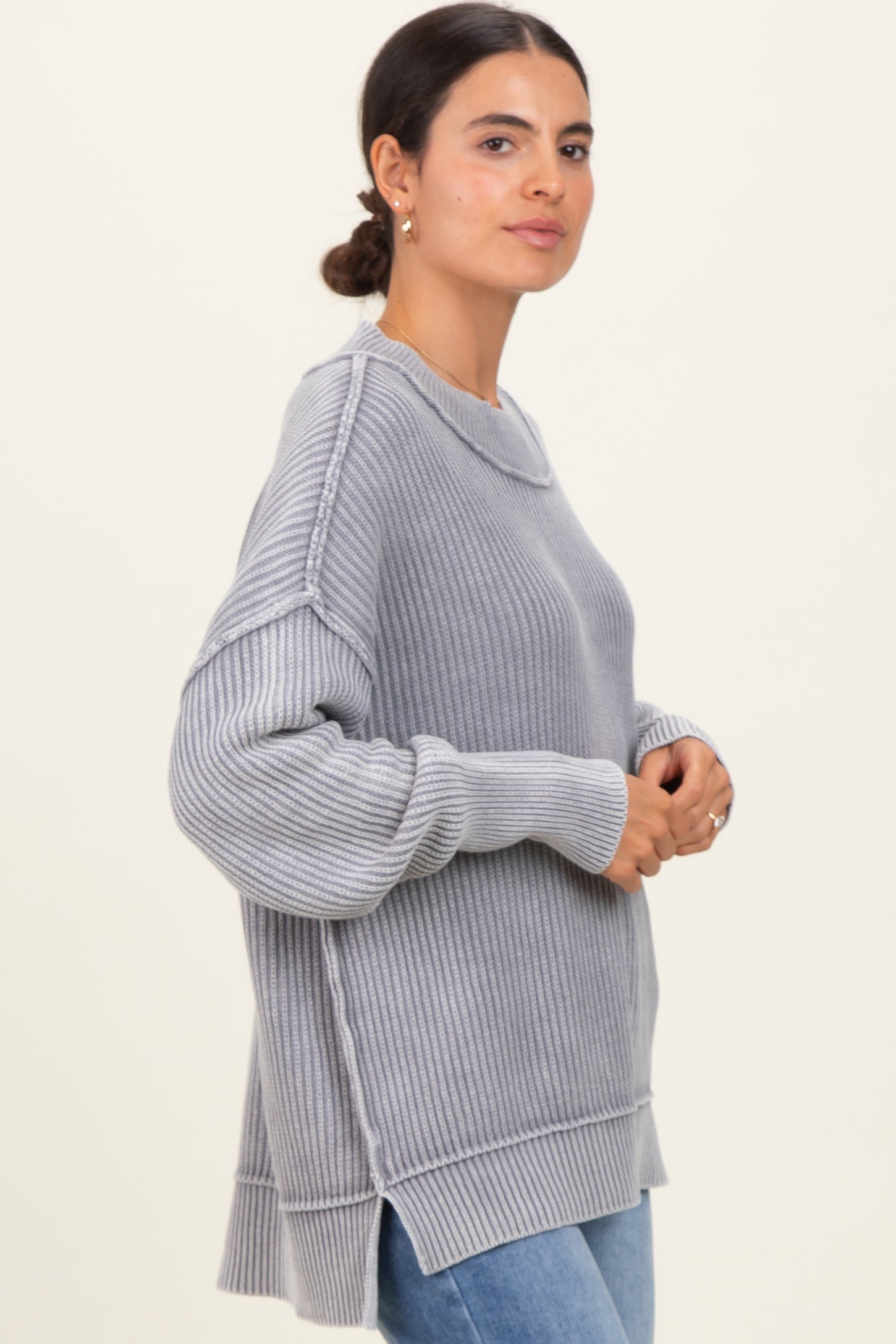 woman wearing a gray ribbed oversized sweater with side slits and long sleeves