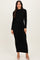 woman wearing a black long sleeve ribbed knit maxi dress with a tie waist detail and beige heels